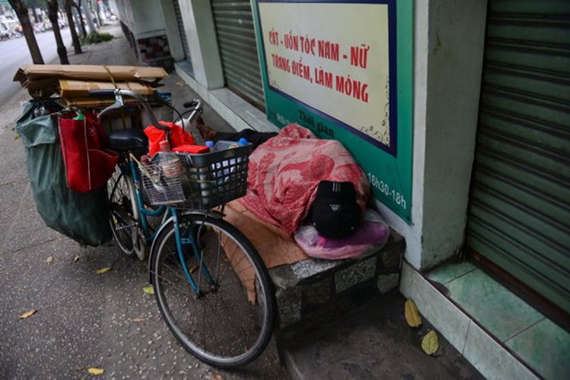 Một người nhặt ve chai co ro ngủ bên lề đường Võ Thị Sáu, quận 3 sau một đêm lao động.