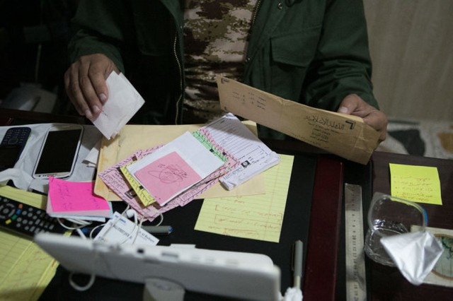 Nhân viên an ninh người Kurd xem xét các tài liệu của IS bên trong hầm ngầm - Ảnh: The Wall Street Journal
