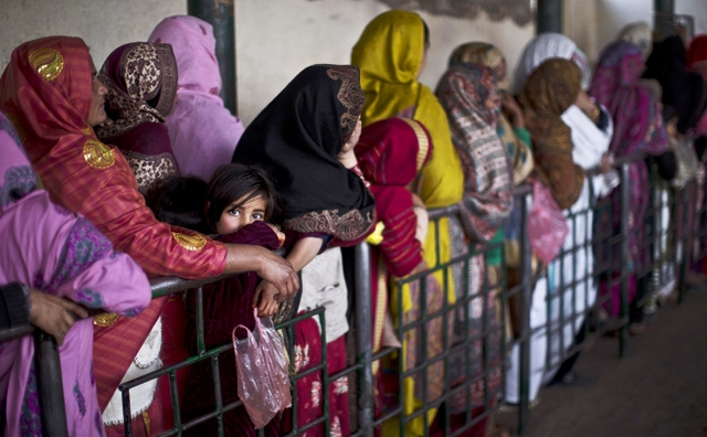 Phụ nữ và trẻ em đứng xếp hàng để chờ nhận gạo tại một trung tâm phân phát thực phẩm tài trợ ở Islamabad, Pakistan.