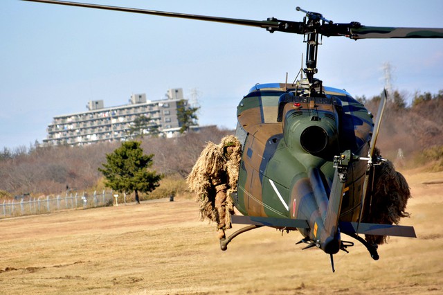 Lính bắn tỉa ngụy trang ngôi trên máy bay trực thăng UH-1 chuẩn bị hạ cánh.