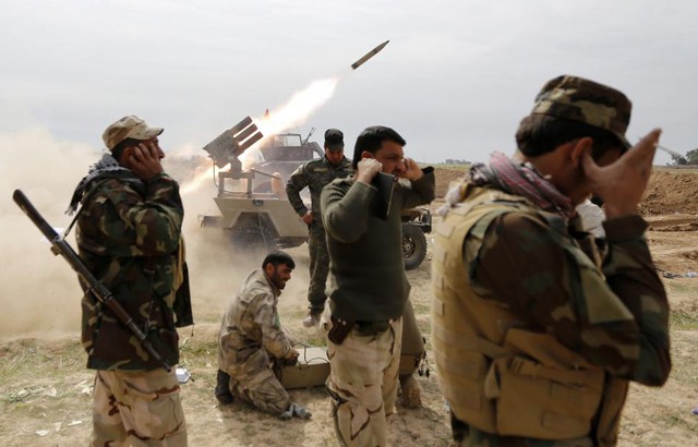 Các chiến binh Hồi giáo dòng Shiite bịt tai trong khi phóng rocket nhằm vào phiến quân Nhà nước Hồi giáo (IS) tại thị trấn al-Alam, Iraq.