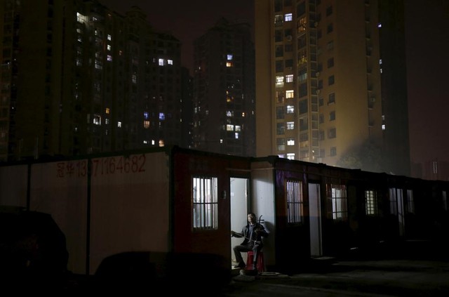 Một công nhân di cư chơi đàn nhị trước khu chung cư cao tầng ở thành phố Vũ Hán, tỉnh Hồ Bắc, Trung Quốc.