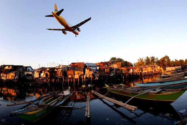 Phi cơ bay sát qua những ngôi nhà lụp xụp tại một làng chài ở miền nam Manila, Philippines.