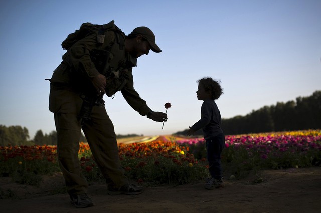 Binh sĩ Israel tặng hoa cho một em bé trên cánh đống gần Kibbutz Nir Yitzhak, miền nam Israel.