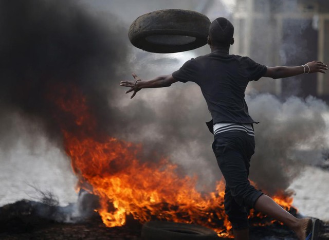 Một người biểu tình đốt lốp xe để làm hàng rào lửa trong cuộc đụng độ với cảnh sát ở Bujumbura, Burundi.