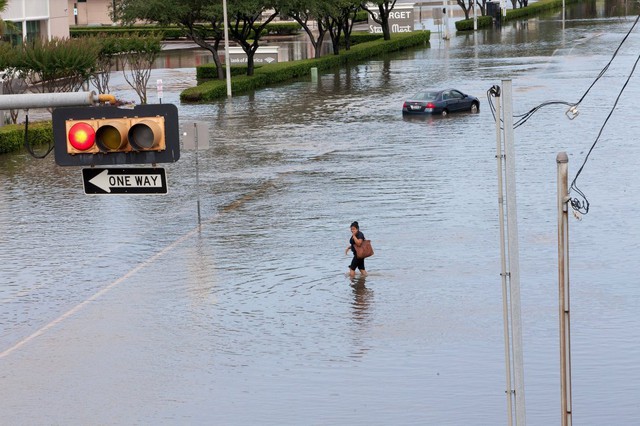 Người phụ nữ đi trên đường phố ngập lụt ở thành phố Houston, Texas, Mỹ.