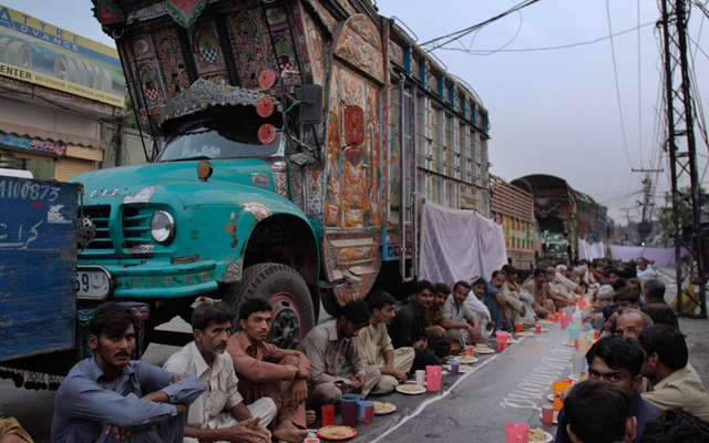 Những tài xế lái xe tải ngồi chờ đến bữa ăn tối trong tháng lễ Ramadan ở Lahore, Pakistan.