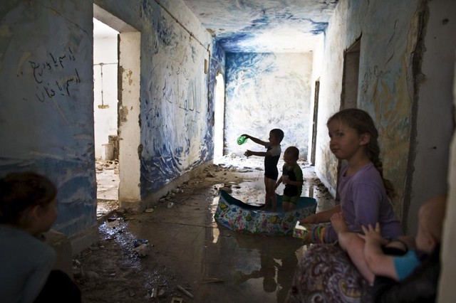 Trẻ em chơi đùa trong bể bơi bằng nhựa bên trong một tòa nhà bỏ hoang tại khu định cư Sa-Nur, Bờ Tây.