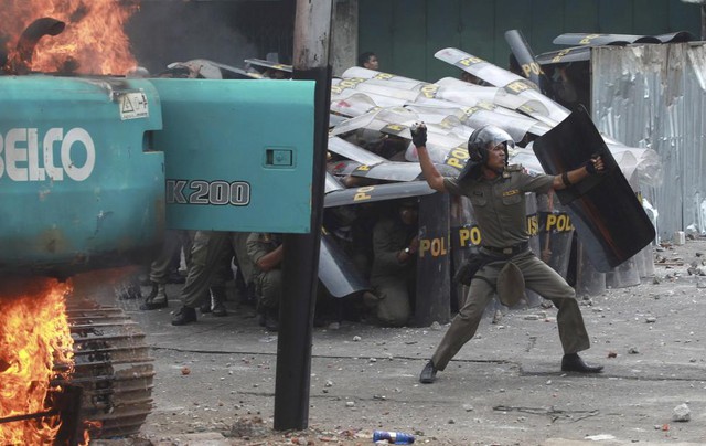 Cảnh sát chống bạo động ném đá đáp trả những người dân biểu tình phản đối thu hồi đất đai ở Jakarta, Indonesia.