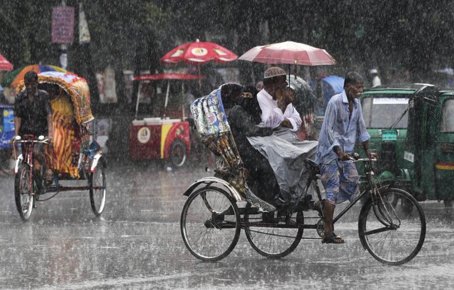 Phu xe ba bánh vất vả chở khách dưới trời mưa lớn tại thành phố Dhaka, Bangladesh.