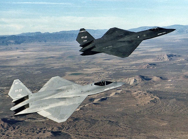 
Nguyên mẫu YF-23 đầu tiên (c/n-87-0800) tên là “Spider” sau này đổi tên thành “Black Widow II” có màu xám than (chiếc ở phía xa) và nguyên mẫu thứ 2 (c/n-87-0801) tên là “Gray Ghost” có 2 tông màu xám nhạt (chiếc ở phía gần). YF-23 do Northorp Grumman/ McDonnell Douglas phát triển
