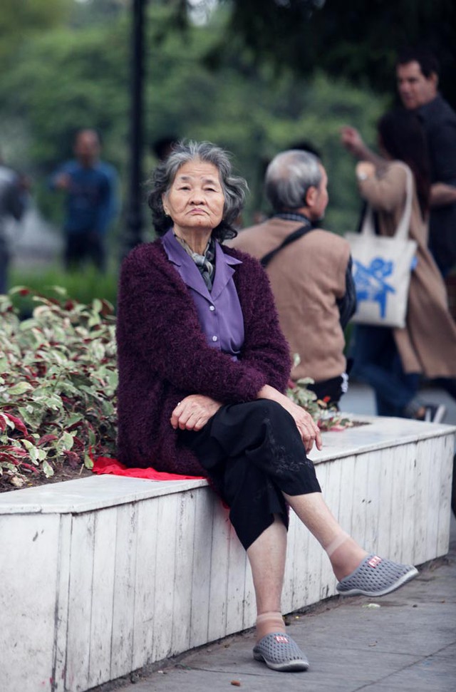 Cụ bà với chiếc áo lông ấm áp, bình thản ngồi ngắm phố phường.