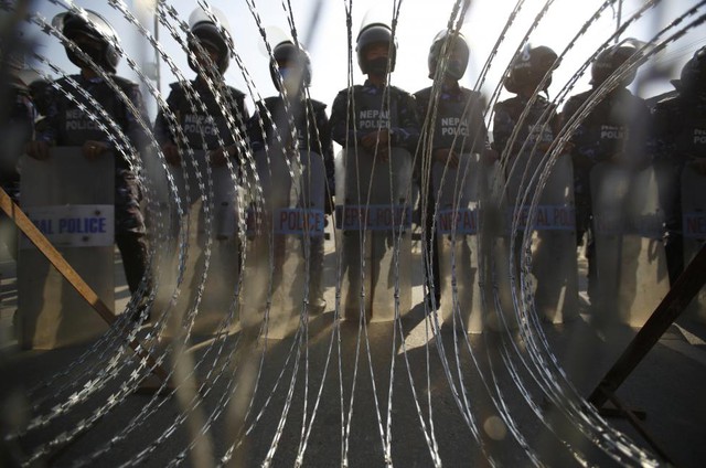 Cảnh sát chống bạo động đứng bảo vệ trước hàng rào thép gai trong cuộc tổng bãi công ở thủ đô Kathmandu, Nepal.