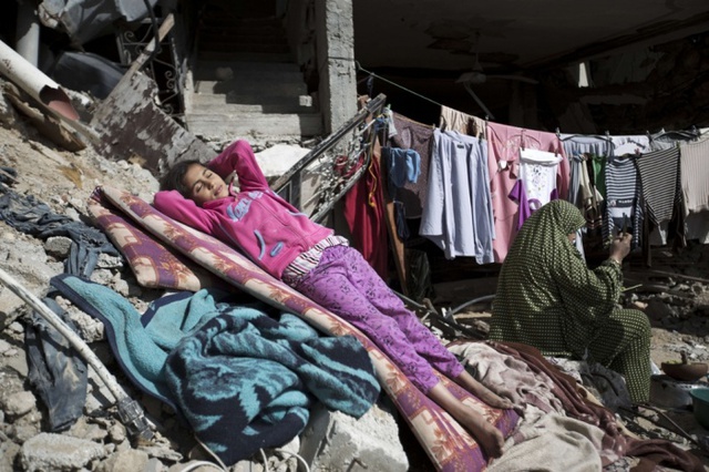 Bé gái người Palestine ngủ trên tấm đệm tại ngôi nhà của cô, bị phá hủy trong đợt pháo kích của quân đội Israel nhằm vào thành phố Gaza.