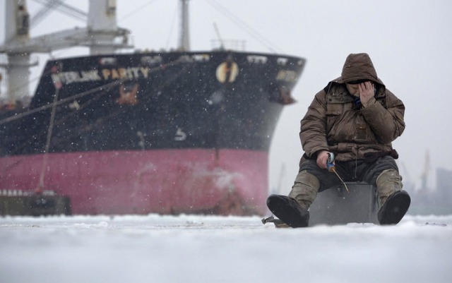 Người đàn ông câu cá qua một hố băng tại St Petersburg, Nga.