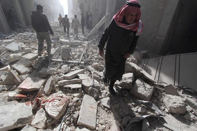 Người đàn ông đi qua đống đổ nát của các tòa nhà bị phát hủy bởi bom đạn ở Aleppo, Syria.