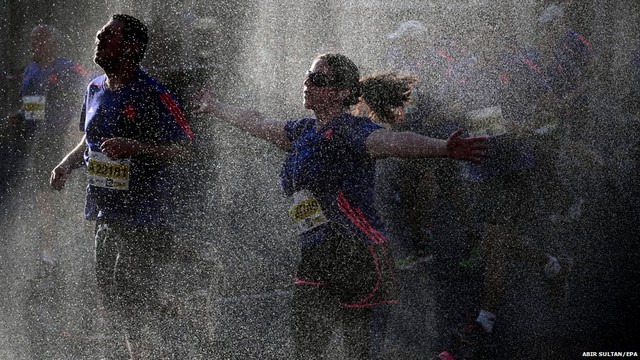 Các vận động viên chạy qua một điểm phun hơi nước trong cuộc thi chạy Tel Aviv Marathon ở Israel.