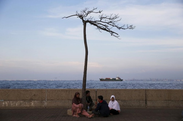 Mọi người ngồi nghỉ dọc một tuyến đê biển ở cảng Muara Baru, Jakarta, Indonesia.