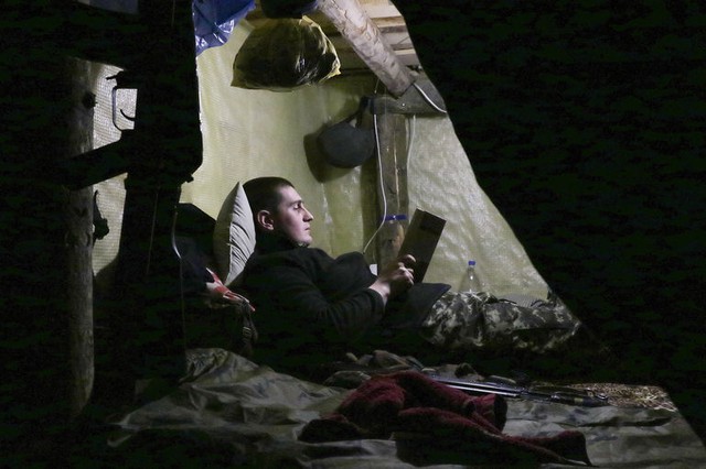 Quân nhân Ukraine nằm đọc sách dưới hầm tại một điểm chốt gần thành phố Mariupol, Ukraine.