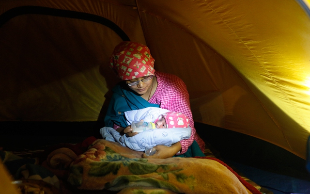 Bà mẹ trẻ cho đưa con chưa đầy 1 ngày tuổi ăn sữa trong một túp lều tạm dành cho các nạn nhân bị ảnh hưởng bởi động đất ở Kathmandu, Nepal.