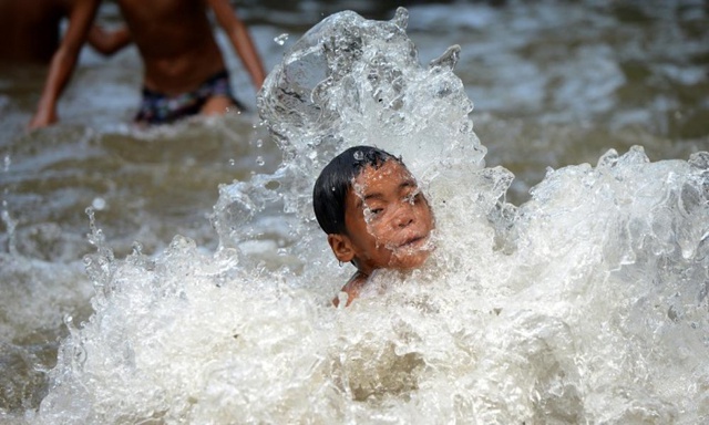 Trẻ em chơi đùa trong nước chảy ra từ đường ống nước vỡ ở thành phố Manila, Philippines.