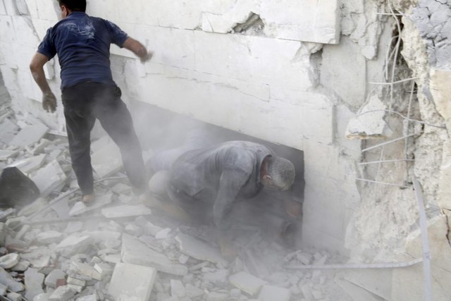 Những người sống sót sơ tán khỏi tòa nhà bị phá hủy trong đợt không kích của quân đội chính phủ nhằm vào thành phố Idlib, Syria.
