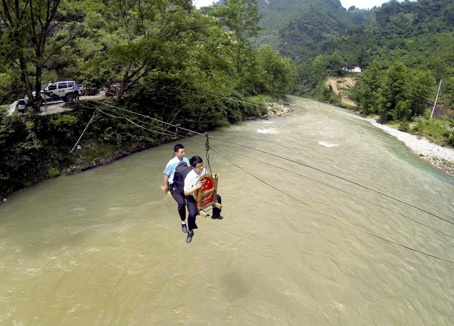 Nhân viên tòa án phải đu dây qua sông để tham dự một phiên tòa lưu động xét xử tranh chấp ly hôn tại ngôi làng Huilong ở thành phố Trùng Khánh, Trung Quốc.