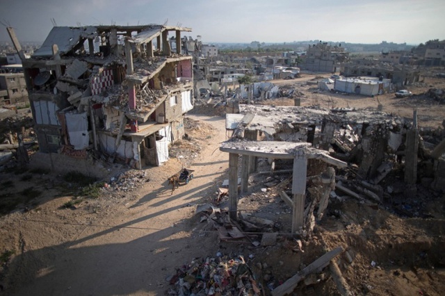 Người dân ngồi trên chiếc xe lừa đi qua những ngôi nhà đổ nát tại thành phố Gaza.