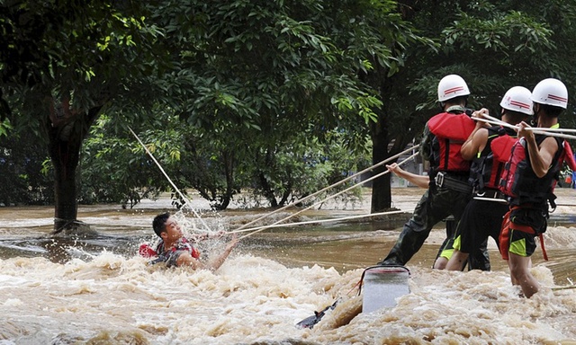 Nhân viên cứu hộ nỗ lực giúp đỡ một người đàn ông mắc kẹt giữa dòng nước chảy siết sau nhiều ngày mưa lớn tại thành phố Quế Lâm, Trung Quốc.