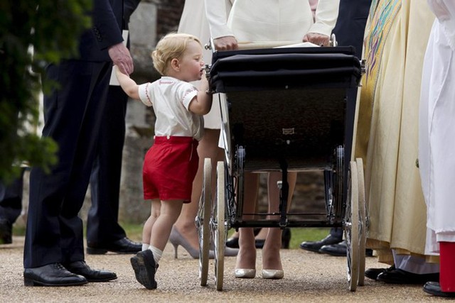 Hoàng tử bé George của Anh nhún chân để nhìn em gái - Công chúa Charlotte - đang nằm trong xe nôi, sau lễ rửa tội tại nhà thờ St. Mary Magdalene ở hạt Norfolk, Anh.