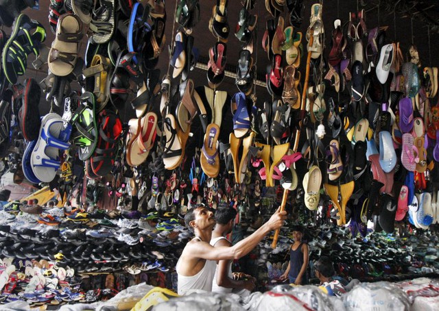 Người đàn ông treo giày dép trong sạp hàng dưới cầu vượt ở thành phố Kolkata, Ấn Độ.
