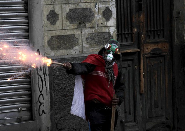 Sinh viên đeo mặt nạ tự chế bắn pháo vào cảnh sát chống bạo động trong cuộc biểu tình ở La Paz, Bolivia.