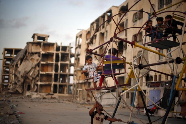 Trẻ em Palestine chơi đua quay gần tòa nhà chung cư bị phá hủy trong đợt không kích năm 2014 của quân đội Israel nhằm vào thị trấn Beit Lahiya ở Dải Gaza.