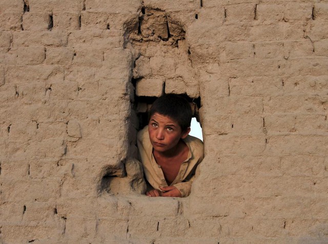 Cậu bé nhìn qua lỗ trên bức tường bằng đất ở ngoại ô thành phố Jalalabad, Afghanistan.