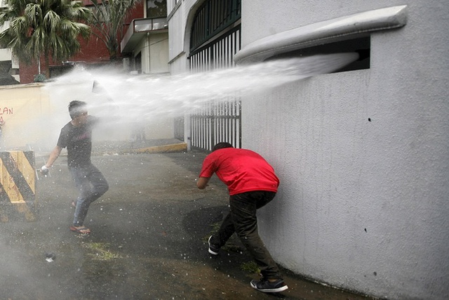 Người biểu tình bị phun vòi rồng khi cố gắng ném bom sơn vào trụ sở của lực lượng vũ trang ở thành phố Quezon City, Philippines.