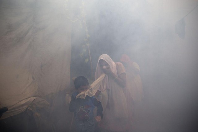 Người dân che mặt khi nhân viên y tế phun thuốc diệt muỗi tại thành phố New Delhi, Ấn Độ.
