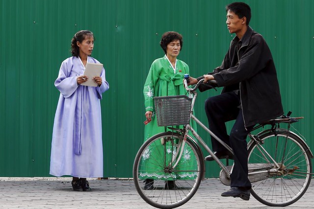 
Một người đàn ông đi xe đạp qua hai phụ nữ mặc quần áo truyền thống của phụ nữ Triều Tiên ở trung tâm Bình Nhưỡng ngày 8.10.
