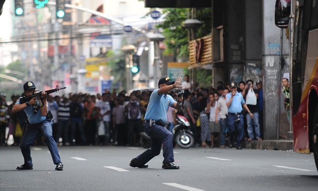 Cảnh sát chĩa súng về phía một kẻ khống chế con tin trên xe bus ở thành phố Manila, Philippines.