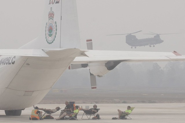 Các nhân viên cứu hỏa của Australia đang nghỉ ngơi cạnh máy bay chở khí chữa cháy Lockheed Hercules, trước khi tham gia dập tắt cháy rừng trên đảo Sumatra, Indonesia.