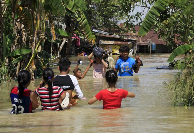 Người dân lội qua nước lũ do bão Koppu gây ra tại thị trấn Calumpit, Philippines.