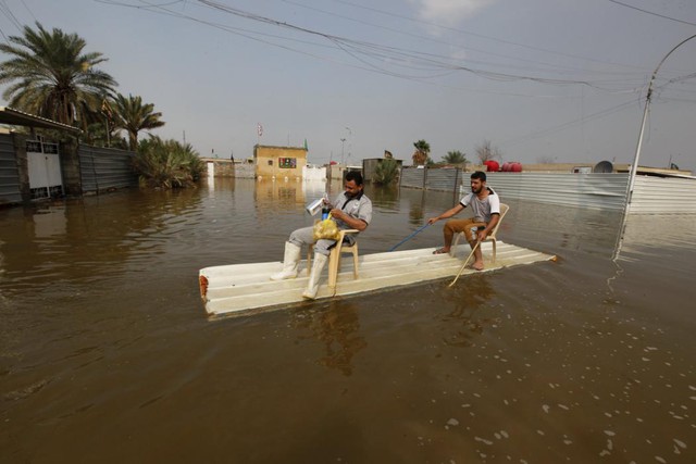 
Mọi người dùng chiếc bè tạm để di chuyển trên đường phố ngập lụt ở Baghdad, Iraq.
