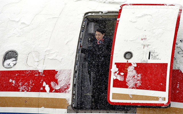 Nữ tiếp viên hàng không chuẩn bị đóng cửa máy bay chở khách phủ đầy tuyết tại sân bay quốc tế ở Bắc Kinh, Trung Quốc.