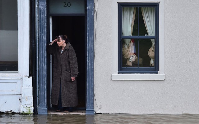 Người dân nhìn nước lũ sắp từ đường phố sắp tràn vào nhà ở thành phố York, Anh.