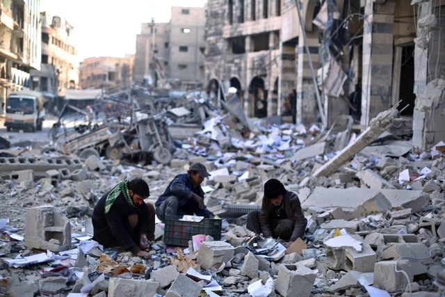
Người dân thu lượm đồ đạc trong đống đổ nát sau một cuộc không kích tại thành phố Damascus, Syria.
