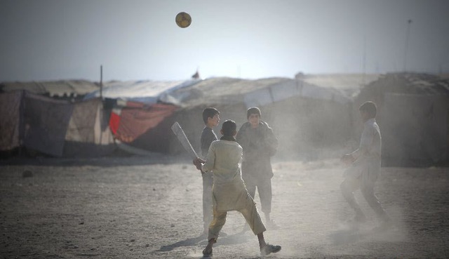 Trẻ em chơi bóng đá trên sân đất tại một khu ổ chuột ở Kabul, Afghanistan.