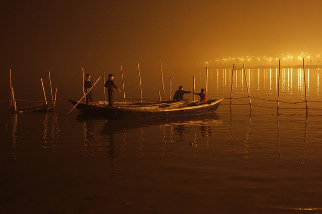 Các cậu bé đang neo thuyền khi sương mù bao phủ bên bờ sông Yamuna vào một buổi tối lạnh giá tại thành phố Allahabad, Ấn Độ.