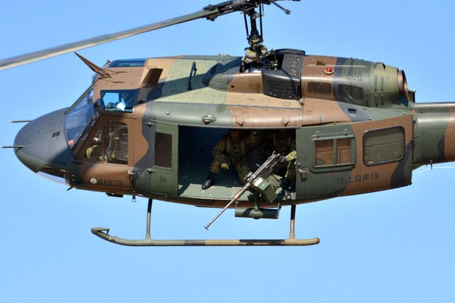 Súng máy hạng nặng trên máy bay trực thăng UH-1 chĩa về phía mục tiêu.