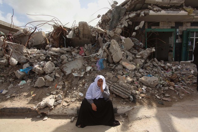 Người phụ nữ Palestine ngồi trước đống đổ nát của một tòa nhà ở thành phố Gaza.