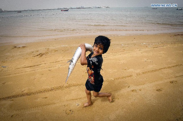 Cậu bé vác cá trên bãi biển tại thành phố cảng Chabahar, miền đông nam Iran.