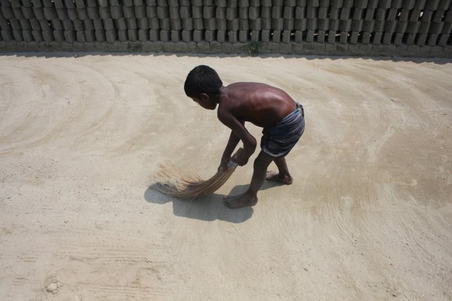 Lao động trẻ em quét sân trong một nhà máy gạch gần Dhaka, Bangladesh.